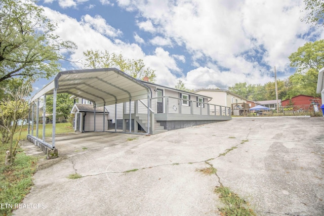 view of parking featuring driveway, a shed, and a carport