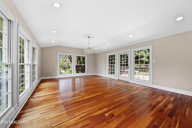 unfurnished living room featuring light wood-type flooring, vaulted ceiling, and a notable chandelier