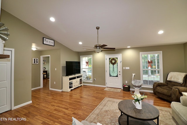 living room featuring light hardwood / wood-style floors, vaulted ceiling, ceiling fan, and plenty of natural light