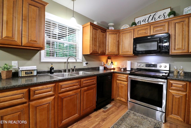 kitchen with lofted ceiling, hanging light fixtures, sink, black appliances, and light hardwood / wood-style floors