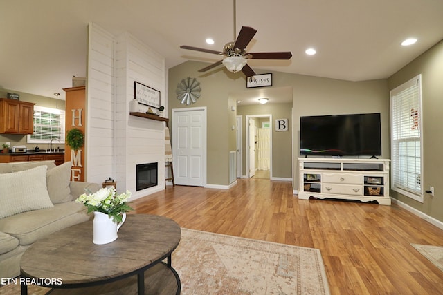 living room with lofted ceiling, light hardwood / wood-style floors, and a healthy amount of sunlight