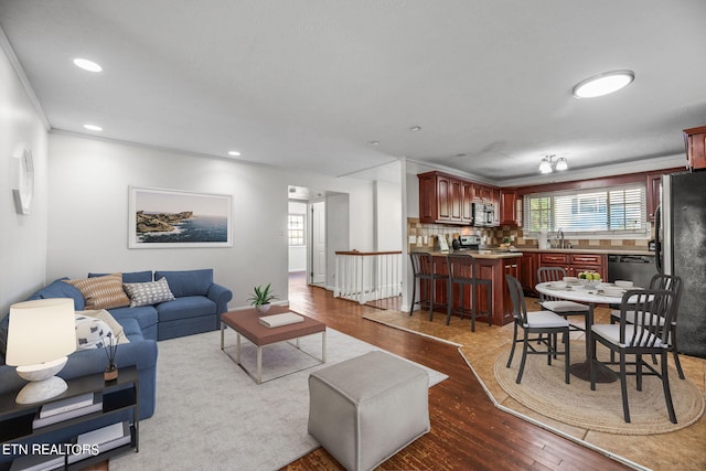 living room featuring sink, light wood-type flooring, and ornamental molding