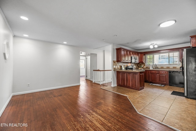 kitchen featuring crown molding, stainless steel appliances, light wood-type flooring, and tasteful backsplash