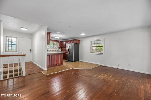 unfurnished living room featuring ornamental molding, plenty of natural light, and dark wood-type flooring