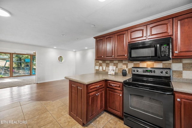 kitchen featuring light hardwood / wood-style floors, black appliances, kitchen peninsula, and backsplash