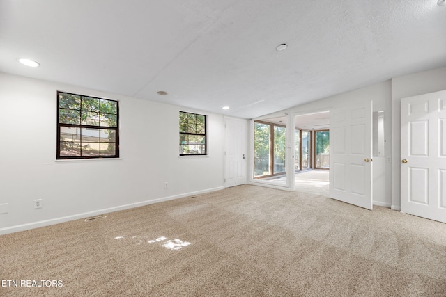 unfurnished room featuring a textured ceiling and light colored carpet