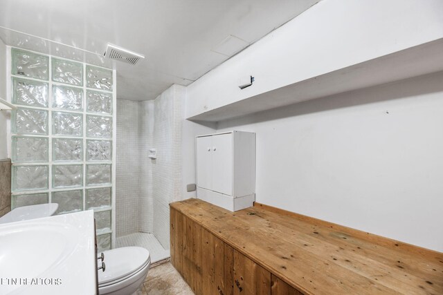 bathroom featuring vanity, toilet, tile patterned floors, and tiled shower