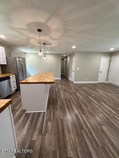 kitchen featuring pendant lighting, white cabinetry, appliances with stainless steel finishes, and butcher block countertops