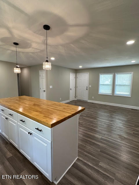 kitchen with white cabinetry, butcher block countertops, dark hardwood / wood-style floors, and decorative light fixtures