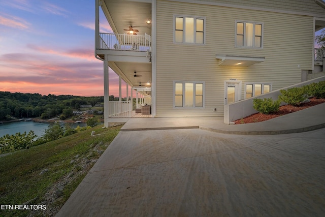 back house at dusk featuring a balcony and a water view