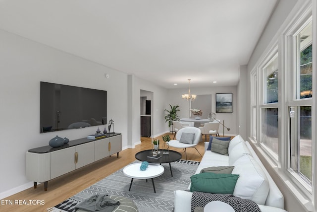 living room featuring an inviting chandelier, light wood-type flooring, and a healthy amount of sunlight