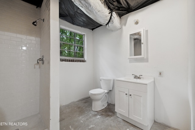 bathroom with vanity, toilet, concrete floors, and tiled shower