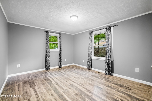 spare room featuring a textured ceiling, a healthy amount of sunlight, and hardwood / wood-style floors