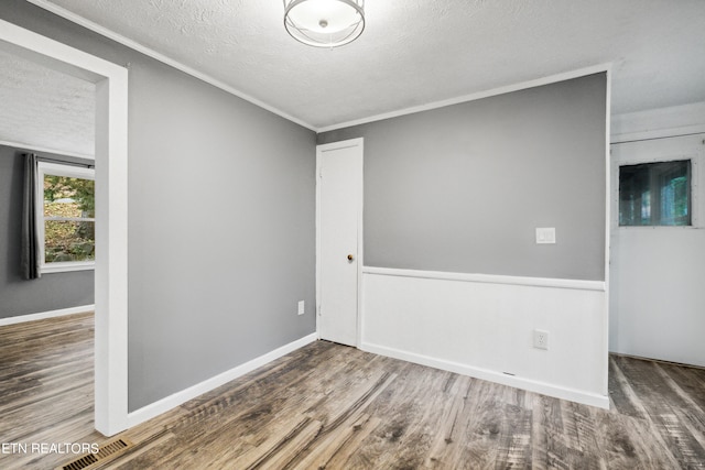 spare room with a textured ceiling, crown molding, and hardwood / wood-style flooring