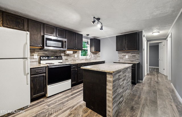 kitchen with white appliances, a textured ceiling, hardwood / wood-style floors, and sink