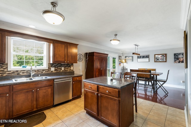 kitchen featuring light tile patterned floors, stainless steel dishwasher, backsplash, a center island, and crown molding