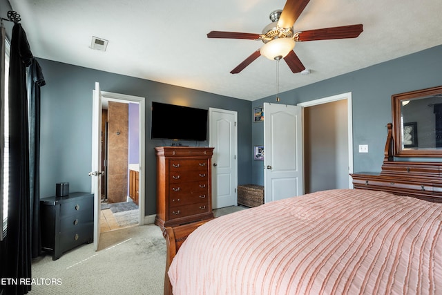 bedroom featuring ceiling fan, light colored carpet, and ensuite bathroom