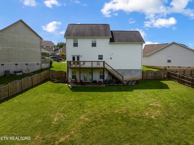 back of house with a wooden deck, a patio, and a yard