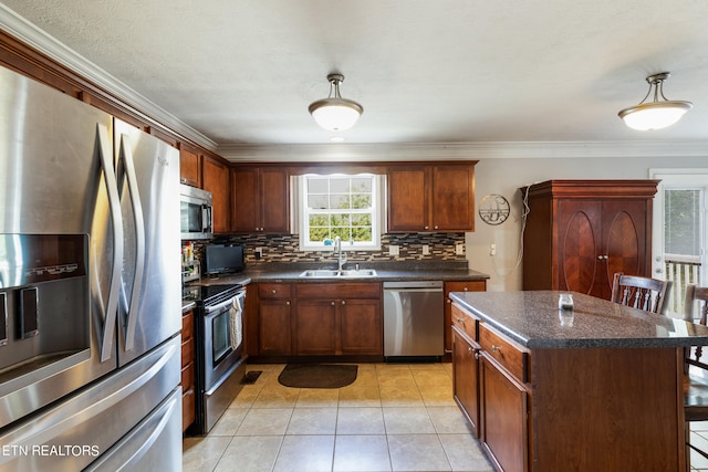 kitchen with appliances with stainless steel finishes, a kitchen bar, a center island, ornamental molding, and sink