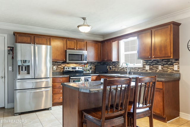 kitchen with appliances with stainless steel finishes, tasteful backsplash, light tile patterned floors, a center island, and sink