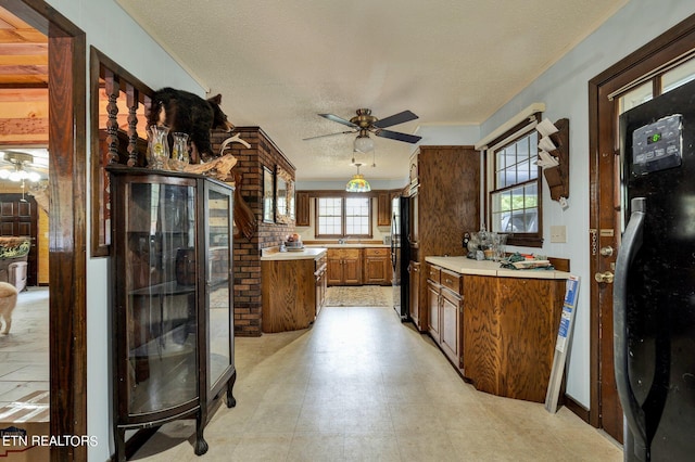 kitchen with ceiling fan, black fridge, and a textured ceiling