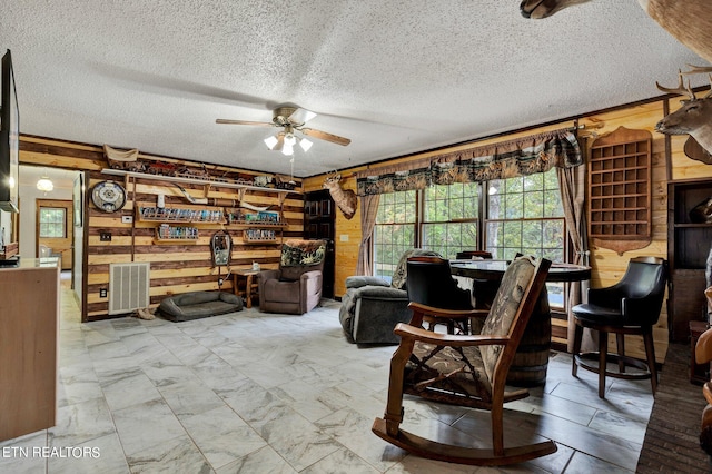 sitting room featuring a textured ceiling, wood walls, and ceiling fan