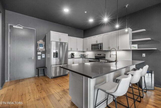 kitchen featuring white cabinetry, kitchen peninsula, appliances with stainless steel finishes, and a breakfast bar area