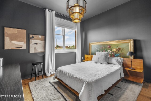 bedroom featuring wood-type flooring and a notable chandelier