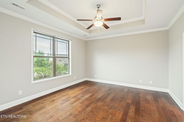 spare room featuring a raised ceiling, hardwood / wood-style floors, and ornamental molding