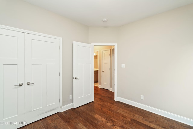 unfurnished bedroom with dark hardwood / wood-style flooring and a closet