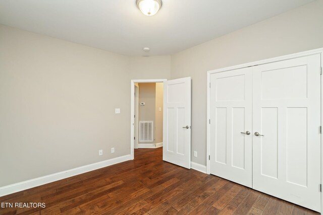 unfurnished bedroom with dark hardwood / wood-style floors and a closet