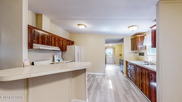 kitchen featuring light hardwood / wood-style floors, a breakfast bar, white appliances, kitchen peninsula, and sink