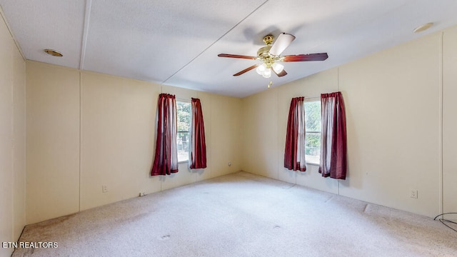 empty room featuring vaulted ceiling, ceiling fan, and carpet floors