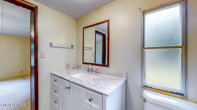 bathroom with a textured ceiling, vanity, and toilet