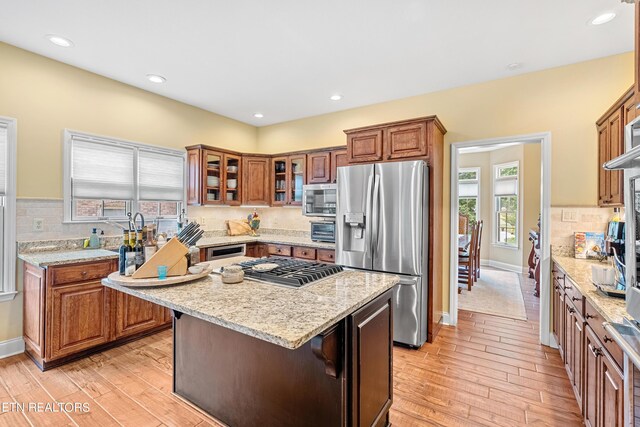 kitchen featuring light hardwood / wood-style floors, a center island, stainless steel appliances, and light stone counters