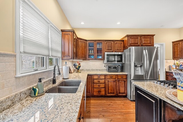 kitchen featuring light stone countertops, stainless steel appliances, light hardwood / wood-style flooring, and sink