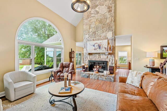 living room featuring high vaulted ceiling, wood-type flooring, and a fireplace