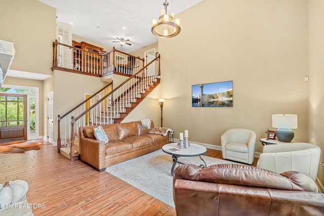 living room featuring an inviting chandelier, light wood-type flooring, and a towering ceiling