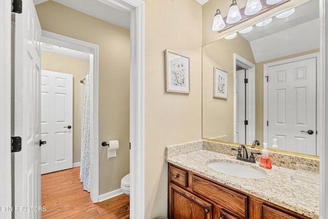 bathroom featuring vanity, toilet, vaulted ceiling, and hardwood / wood-style flooring