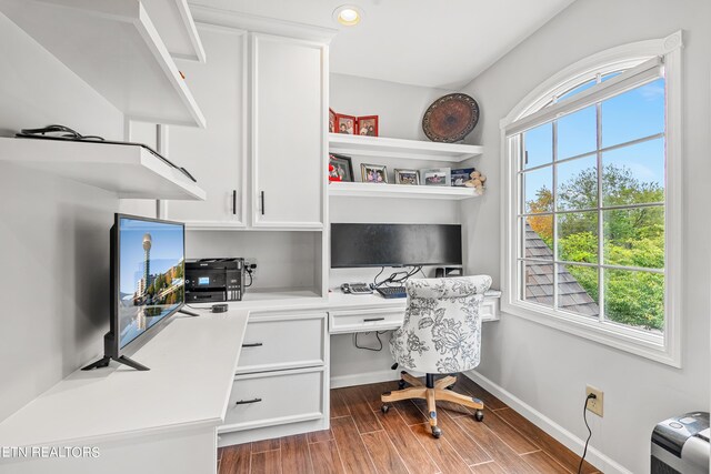 home office with built in desk and dark wood-type flooring