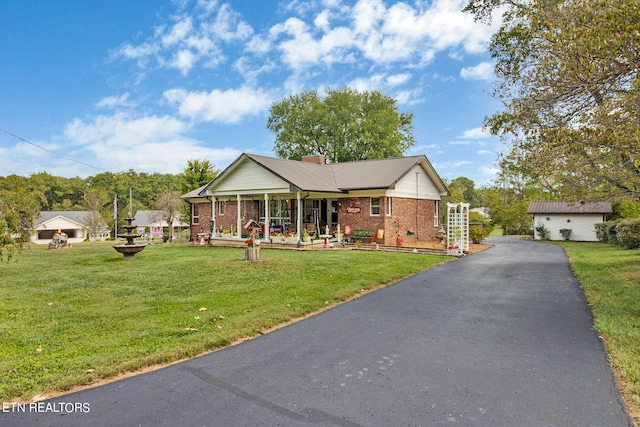 view of front of house with an outbuilding, a garage, covered porch, and a front yard