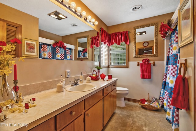 bathroom with a textured ceiling, vanity, and toilet