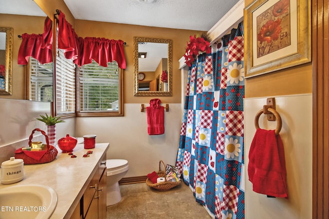 bathroom with a textured ceiling, vanity, and toilet