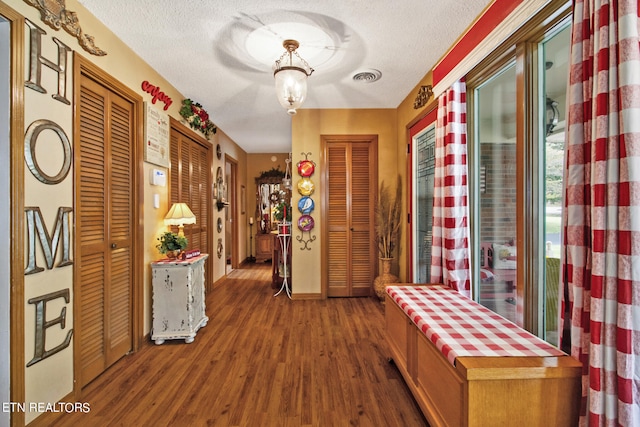 hall featuring a textured ceiling and dark hardwood / wood-style floors