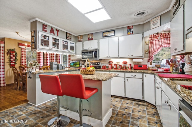 kitchen featuring appliances with stainless steel finishes, a kitchen breakfast bar, white cabinetry, a kitchen island, and dark hardwood / wood-style flooring