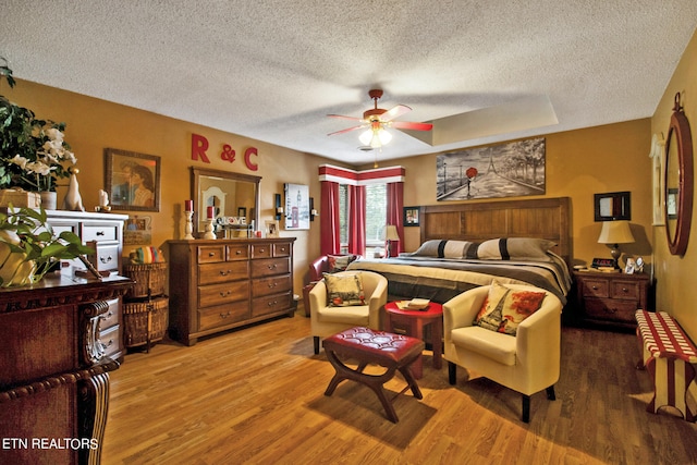 bedroom with wood-type flooring, a textured ceiling, and ceiling fan