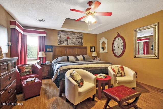 bedroom with wood-type flooring, ceiling fan, and a textured ceiling