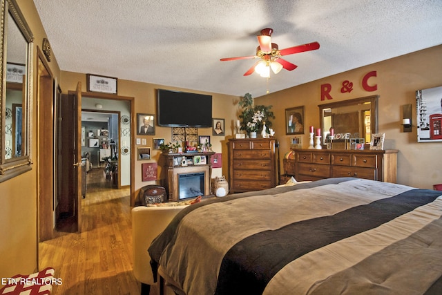 bedroom with light wood-type flooring, a textured ceiling, and ceiling fan