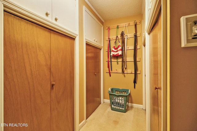 hallway with light colored carpet and a textured ceiling