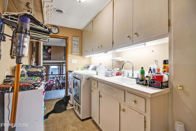 clothes washing area with washer and clothes dryer, cabinets, and sink